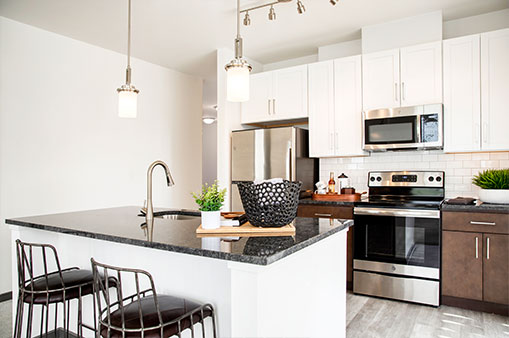 kitchen at Dartmoor Place at Oxford Square apartments in Hanover MD with stainless steel appliances, white cabinets and separate island with sink and chairs | Dartmoor Place