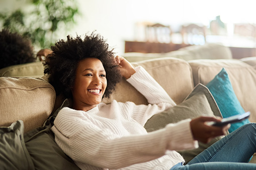 smiling woman on couch with TV remote | Dartmoor Place
